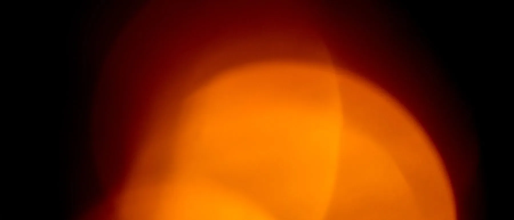 Brilho abstrato laranja e vermelho sobre fundo escuro, evocando calor e inflamação