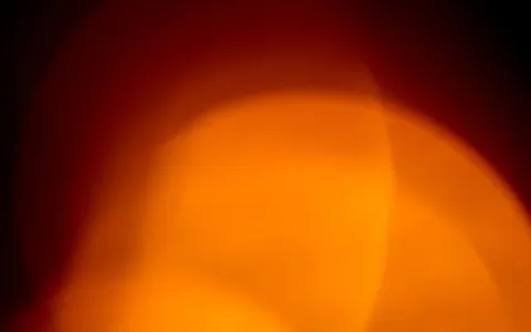 Brilho abstrato laranja e vermelho sobre fundo escuro, evocando calor e inflamação